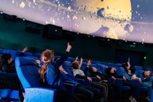 People of all ages are enthralled by the immersive displays in a planetarium dome.