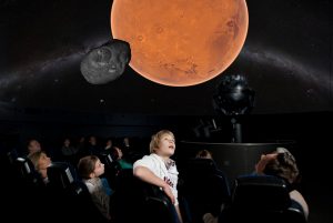Planetarien begeistern Menschen. Vater und Sohn betrachten einen Planeten und einen Asteroiden.